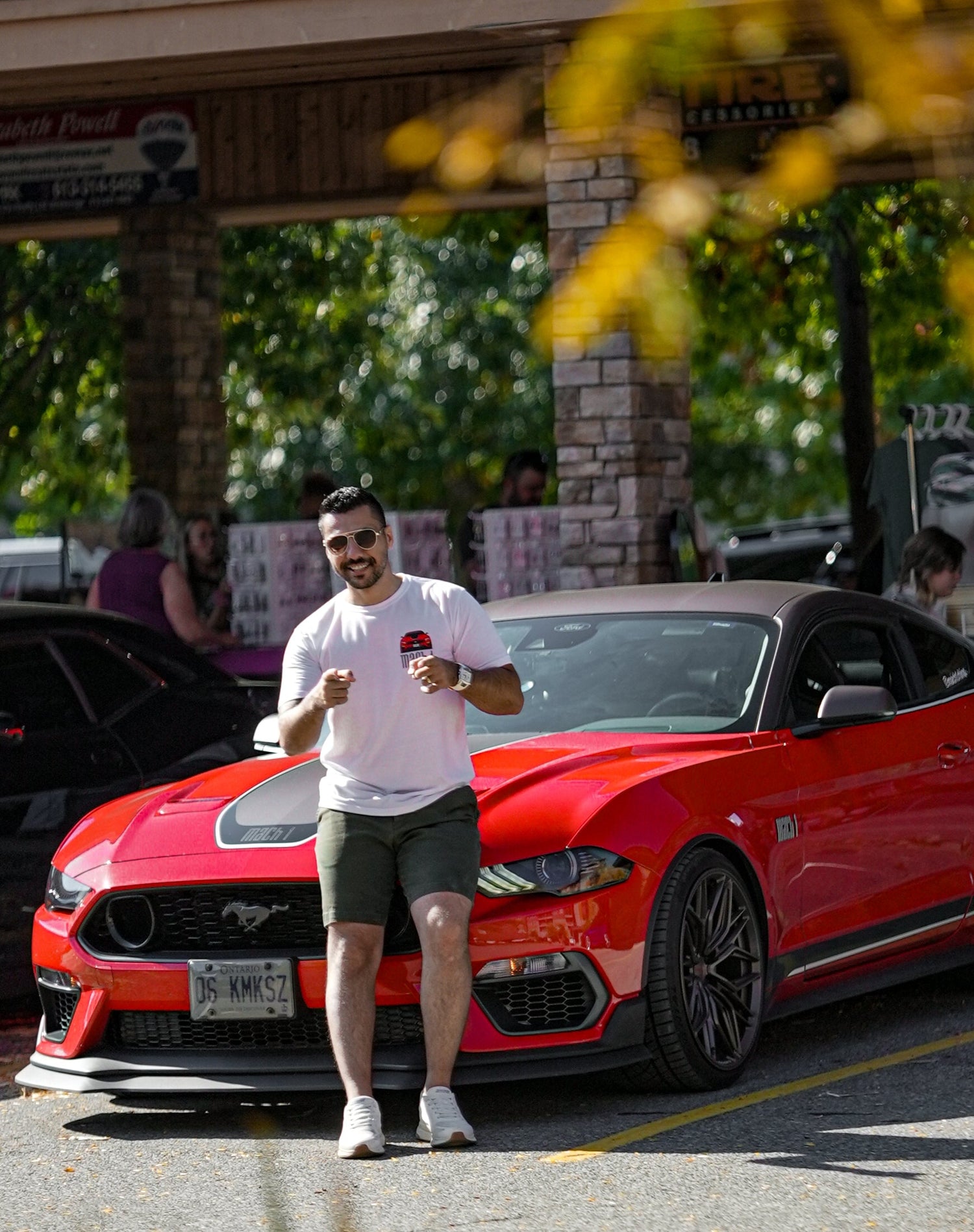 Man standing next to a red sports car in a parking lot