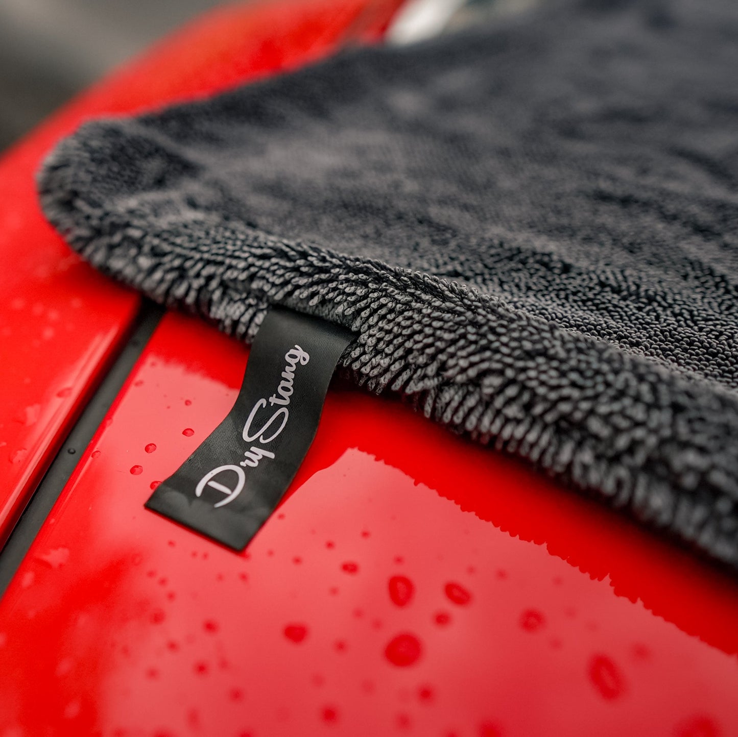 Gray microfiber towel on a red car with 'Dry Savvy' branding.
