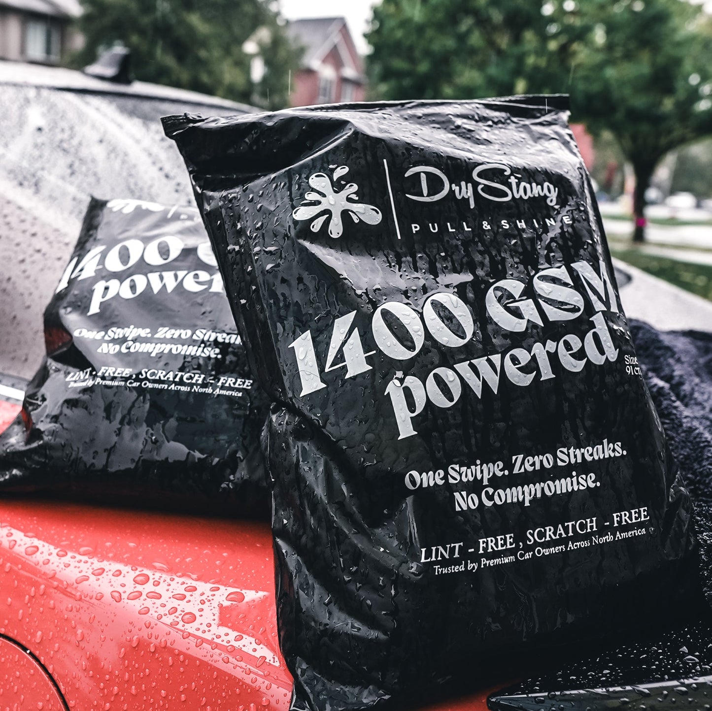 Black car wax packet with text in front of a red car