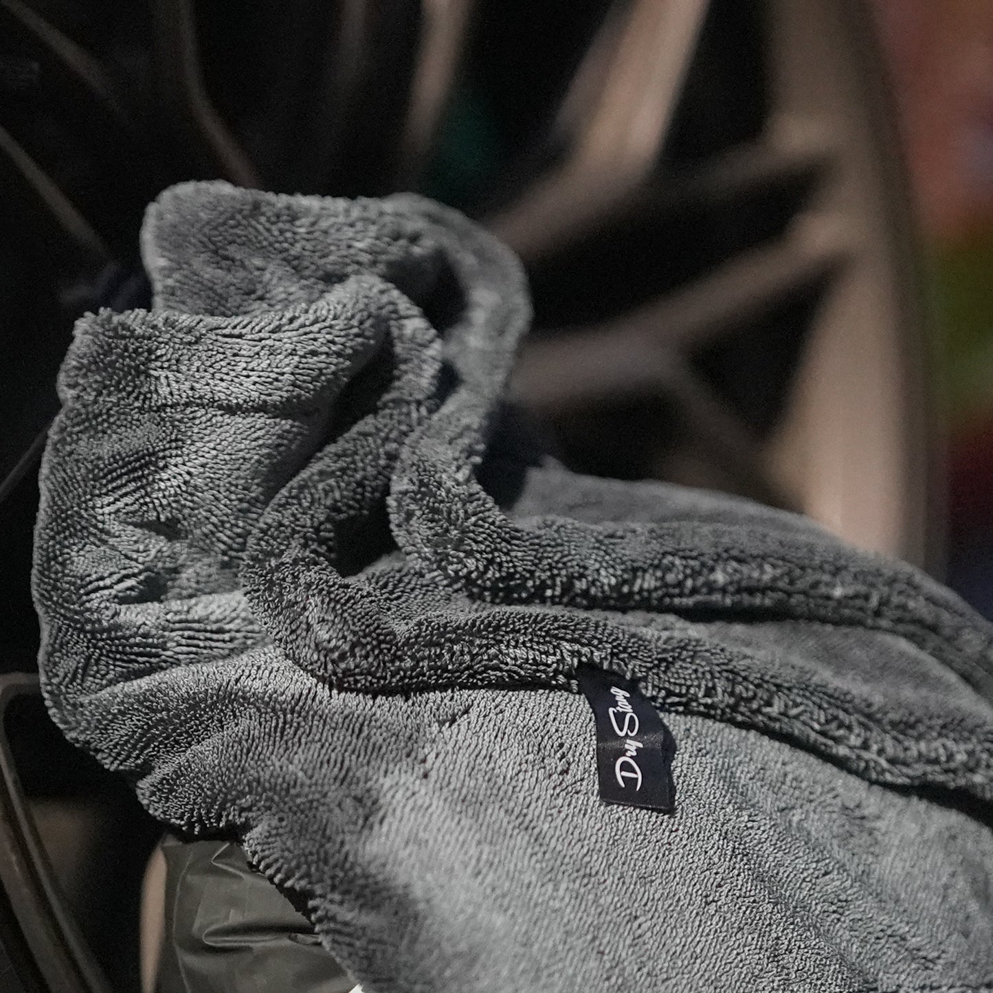 Gray car drying microfiber towel with a brand label on a blurred background
